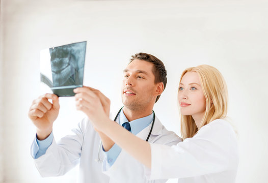 smiling male doctor or dentist looking at x-ray