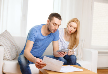 busy couple with papers and calculator at home