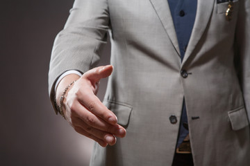 Businessman in suit offering to shake hands.