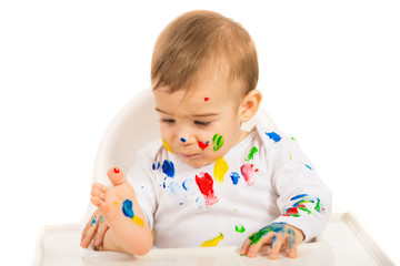 Baby boy looking at colorful paints
