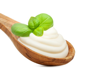 Cream in wooden spoon and basil leaves spice isolated on white
