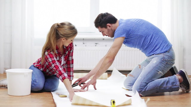 smiling couple cutting wallpaper