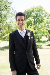 Groom in tuxedo standing at garden