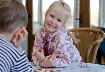 Beautiful little girl playing a game of checkers