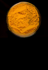 Powdered tumeric spices over black background