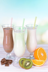 Obraz na płótnie Canvas Milk shakes with fruits on table on light blue background