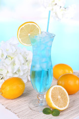 Glass of cocktail on table on light blue background