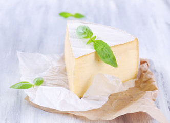 Tasty Camembert cheese with basil, on wooden table