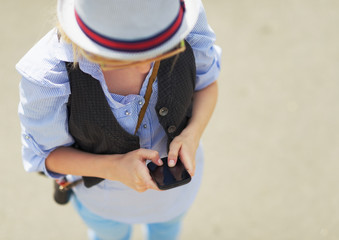 Young hipster writing sms on city street