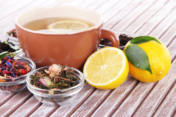 Cup of tea with aromatic dry tea in bowls on wooden background