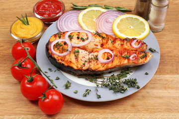 Tasty grilled salmon with vegetables, on wooden table