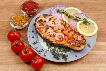 Tasty grilled salmon with vegetables, on wooden table