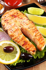 Tasty grilled salmon with lemon and vegetables, on wooden table