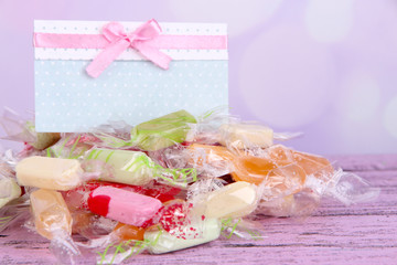 Tasty candies with card on table on bright background