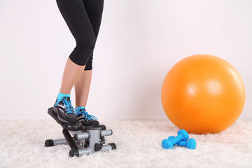 Young beautiful fitness girl exercising on stepper in gym
