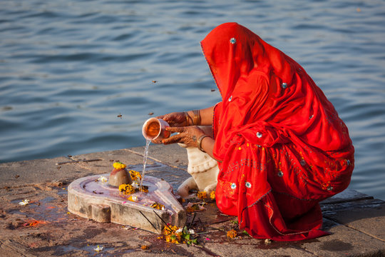 Indian woman performs morning pooja on holy river Narmada ghats