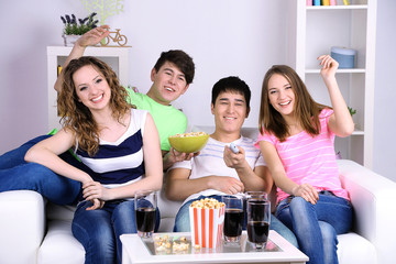 Group of young friends watching television at home