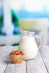 Almond milk in jug with almonds in bowl,