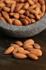 Almonds in bowl on color wooden background