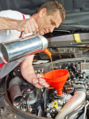 Motor mechanic changes the oil of a car