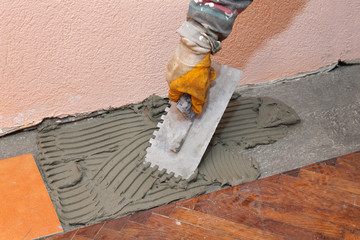Home renovation, trowel spreading mortar for ceramic tile