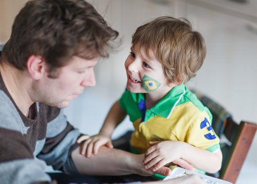 Father painting flag on face of little son