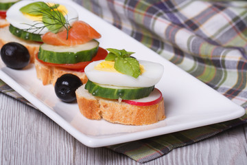 canape with boiled egg, cucumber, radish, salmon and basil