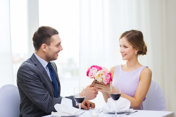 smiling man giving flower bouquet at restaurant