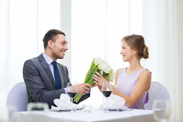 smiling man giving flower bouquet at restaurant