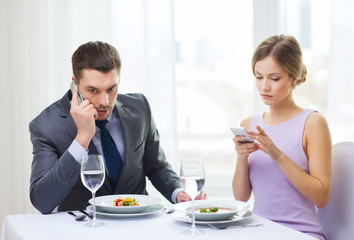busy couple with smartphones at restaurant