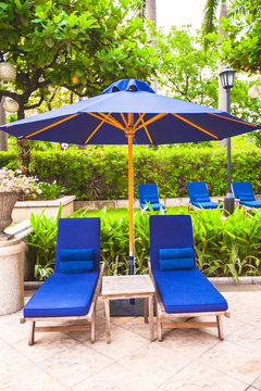 Two chairs with umbrellas near swimming pool in luxury hotel