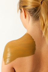 Die junge nackte Frau wird mit Heilerde behandelt