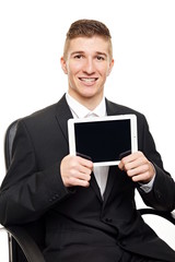 Young businessman at suit sitting and shows tablet pc