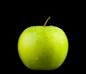 green apple with droplets of water on black background