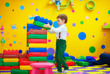 happy kid building blocks in kindergarten