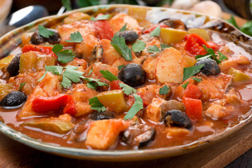 fish stew in tomato sauce on a plate, close-up, selective focus