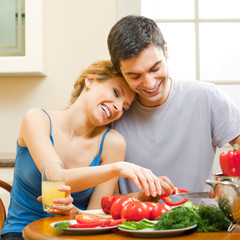 Cheerful young cooking couple at home