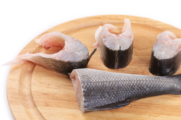 Steaks and tail of seabass on wooden platter.