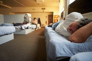 Men Lying On Beds In Homeless Shelter