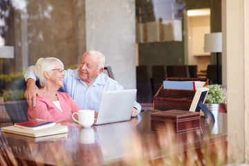 Senior Couple Using Laptop On Desk At Home