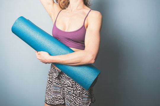 Athletic young woman holding a yoga mat