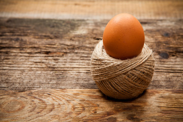 Egg in rope coil on old wooden table