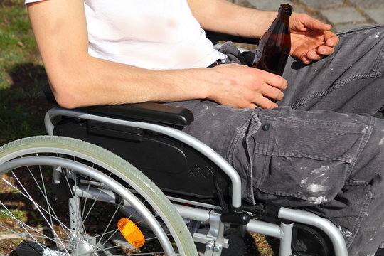 Bedürftiger im Rollstuhl mit Bierflasche