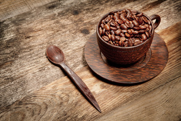 Wooden cup with coffee-beans on wooden table