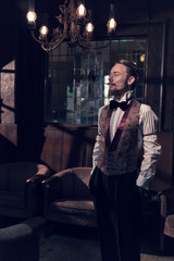 Fototapeta na wymiar Vintage 1900 fashion man with beard. Standing in old wooden room