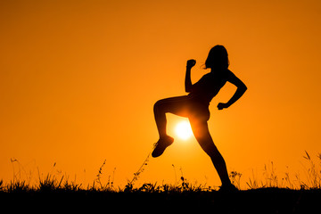 Silhouette of kick boxing girl exercising kick.