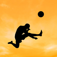 Fototapeta na wymiar Silhouette boy jumping to kick the ball on the sky.