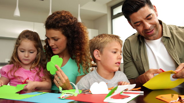 Happy parents and children doing arts and crafts at kitchen