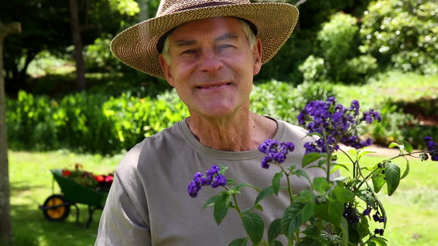 Retired man gardening and smiling at camera