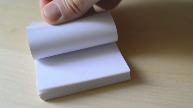 Man flipping pages of small book